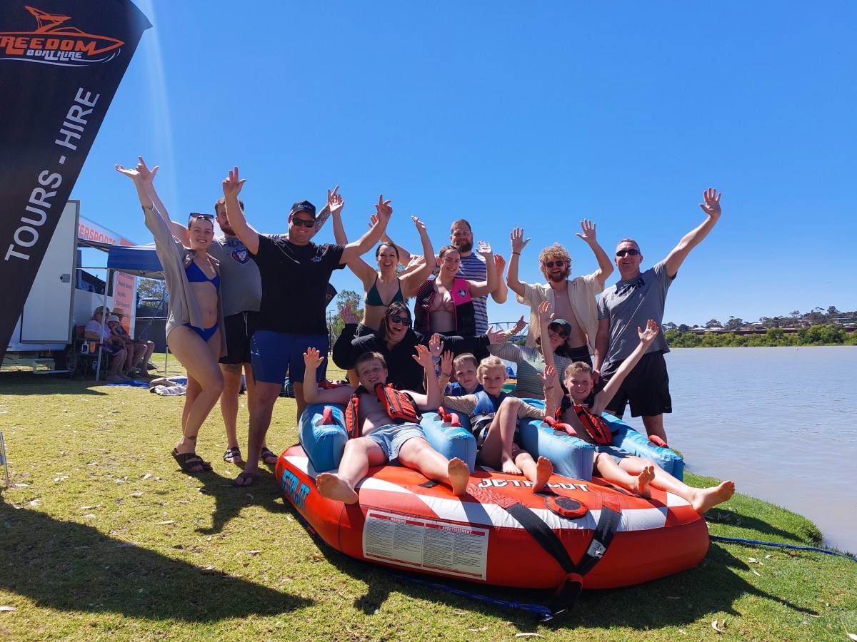 Group celebrating by a lake with kids sitting on an inflatable.
