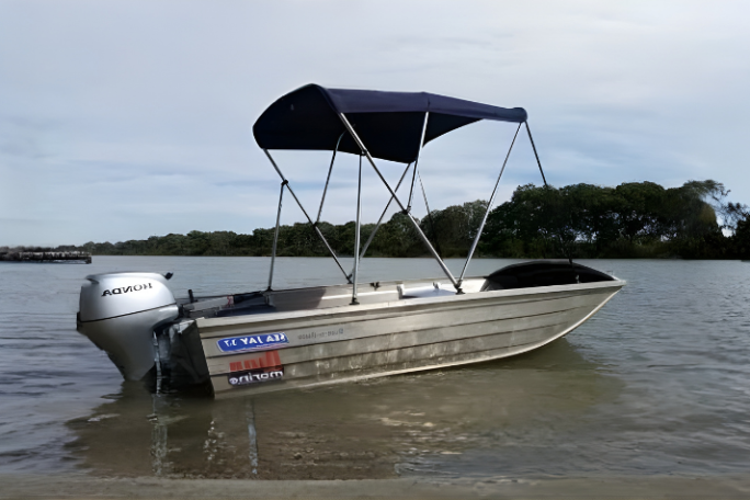 Small motorboat with canopy floating on a calm river.