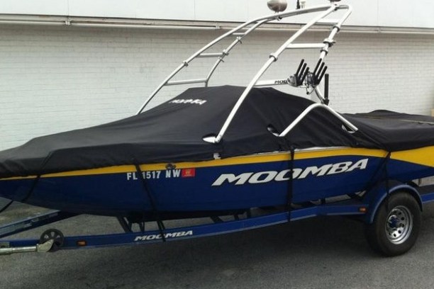 Covered blue and yellow Moomba boat on trailer outside.