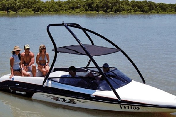 People sitting on a white speedboat in calm waters.