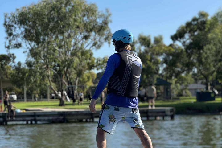 Person on an electric surfboard gliding over a lake.