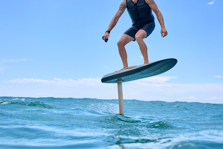 Person riding a hydrofoil surfboard over ocean waves.