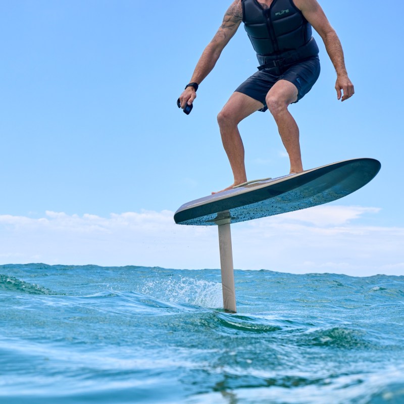 Person riding a hydrofoil surfboard over ocean waves.