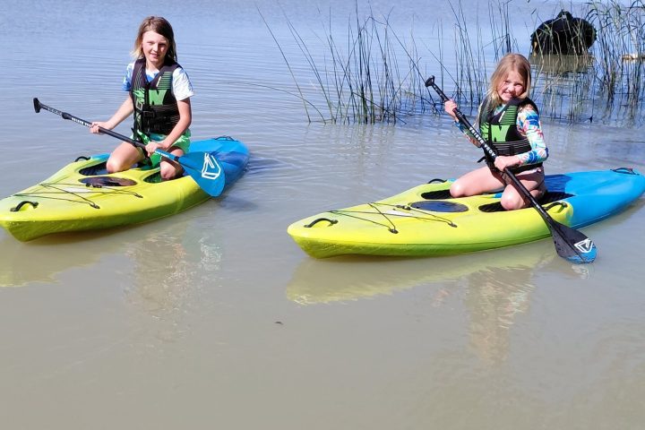 Two people kayaking on a calm body of water.