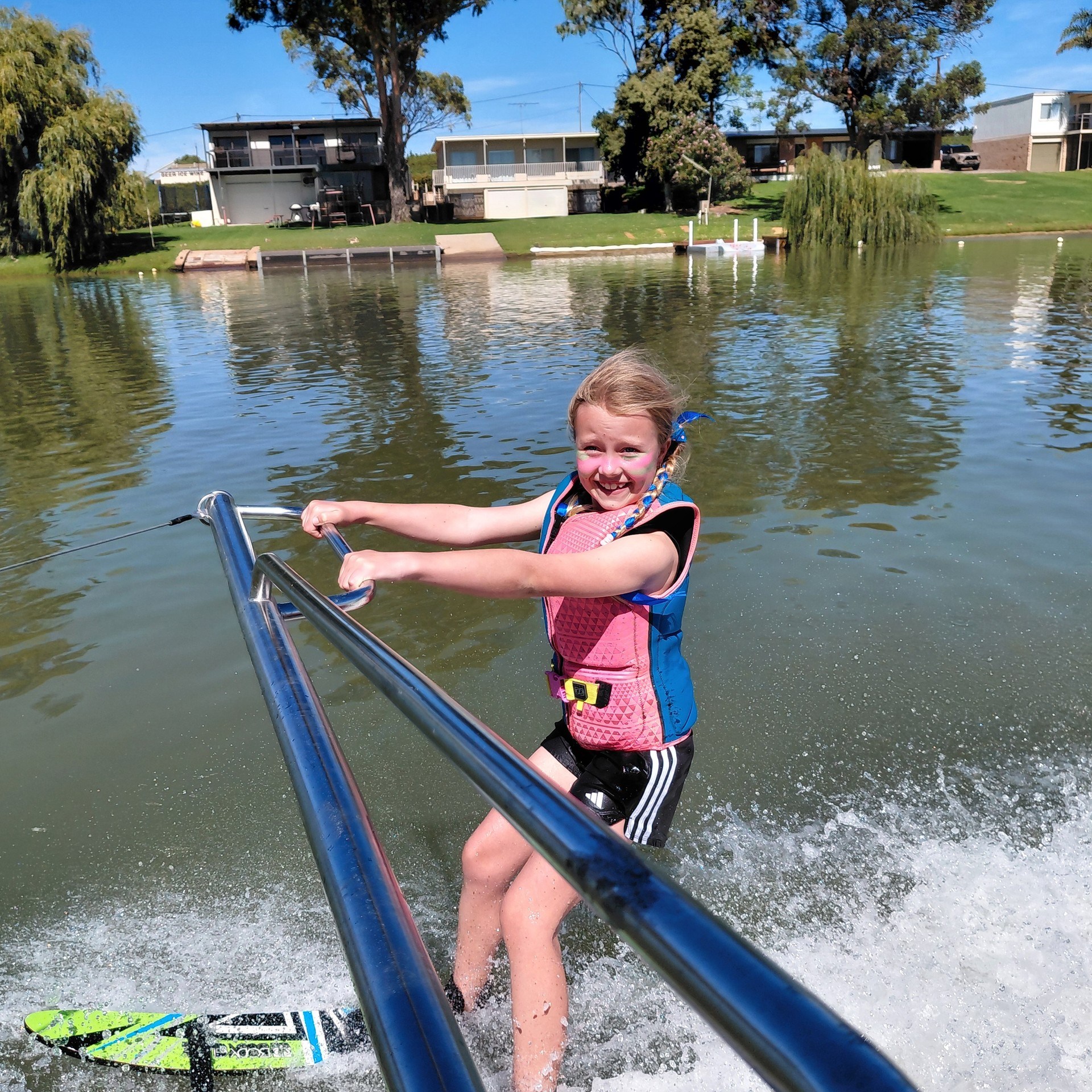 Child waterskiing on a lake with a joyful expression.