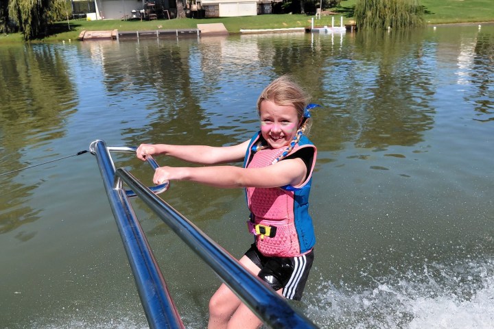 Child waterskiing on a lake with a joyful expression.